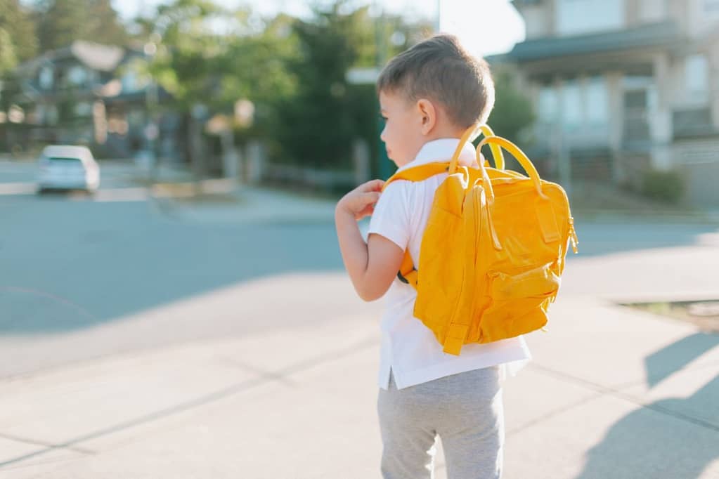 un bambino con zainetto giallo che sta andando a scuola