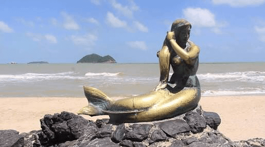 Foto della sirenetta della spiaggia Samila di Songkhla con le isole del topo e del gatto in secondo piano