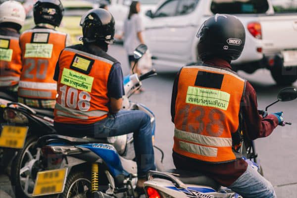 motociclisti tassisti con casco di schiena in attesa di clienti