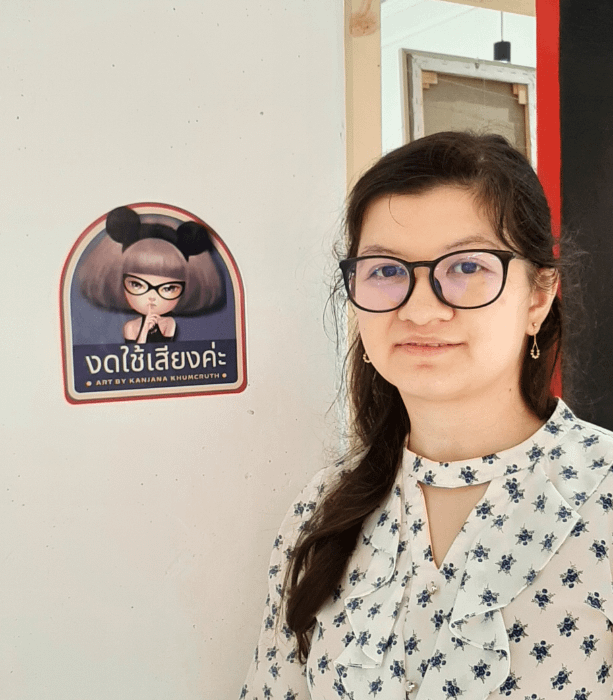 ragazza accanto ad adesivo con nome dell'artista della mostra
