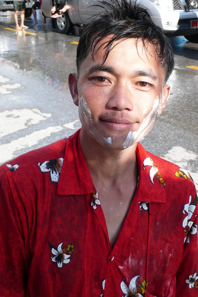 primo piano di un ragazzo thailandese con il volto coperto di borotalco durante il songkran