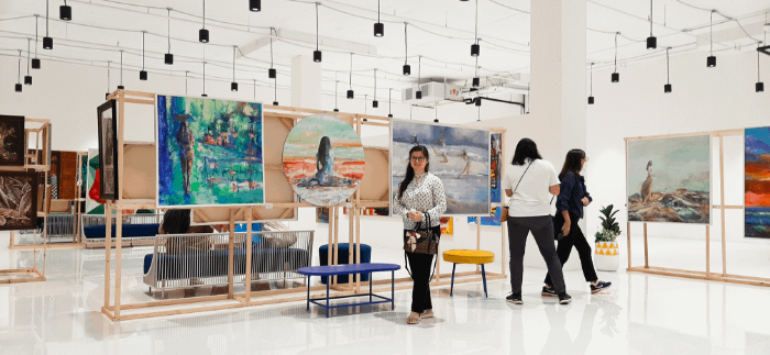 ragazza di fronte a diversi quadri in una esposizione artistica