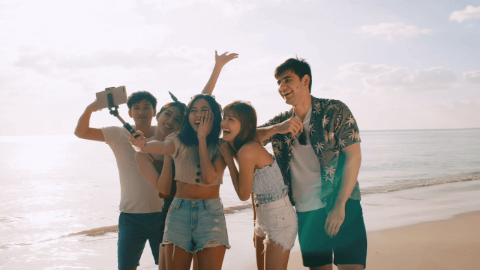 ragazzi asiatici in spiaggia a farsi un selfie di gruppo