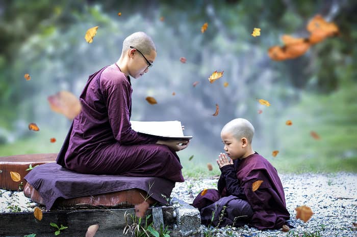 due bambini vestiti da monaci, con vesti viola, rasati, intenti a studiare le scritture buddiste