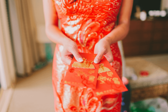 ragazza con abito cinese tradizionale rosso che distribuisce gli Ang Pao