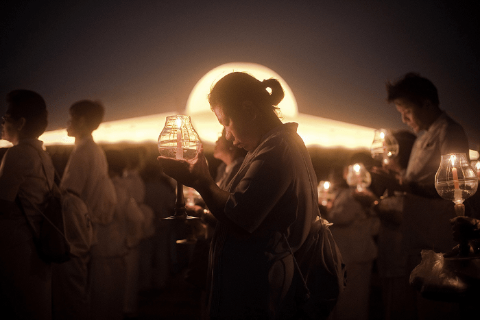 persone buddiste radunate di notte per pregare insieme, ognuno con una candela in mano