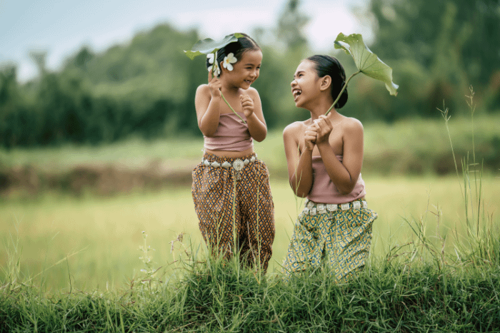 due bambine thailandesi in costumi tradizionali che ridono in una risaia