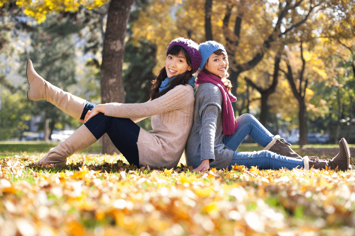 amiche sedute per terra in un parco schiena contro schiena