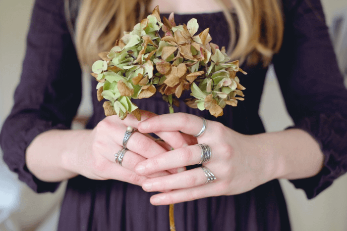 donna con in mano un bouquet di ortensie mezzo appassito