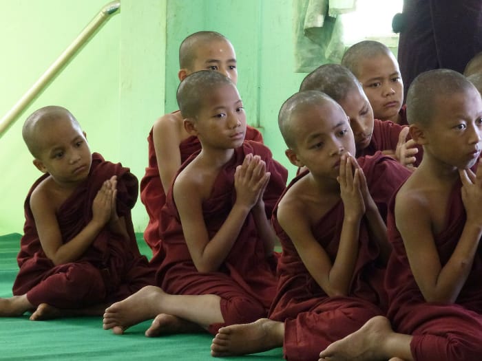 Giovani monaci bambini inginocchiati nel tempio mentre pregano