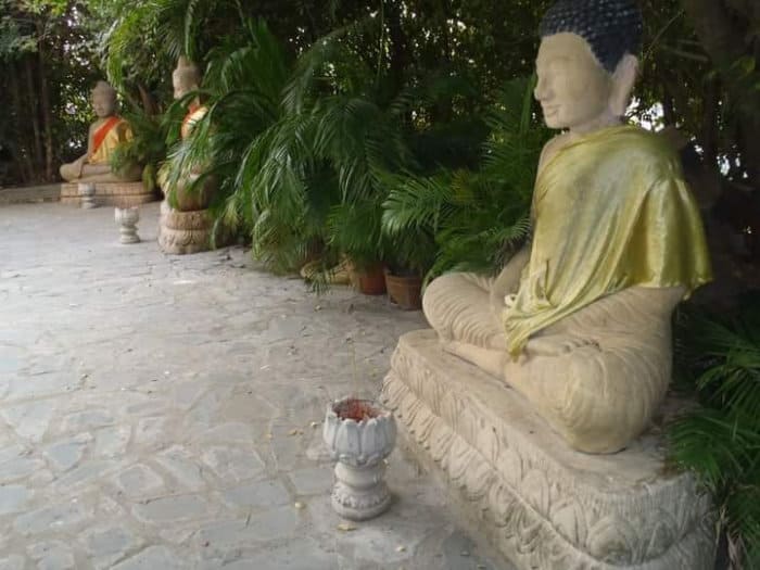 Statue di Buddha rialzate dal terreno su un piedistallo decorato con petali di loto